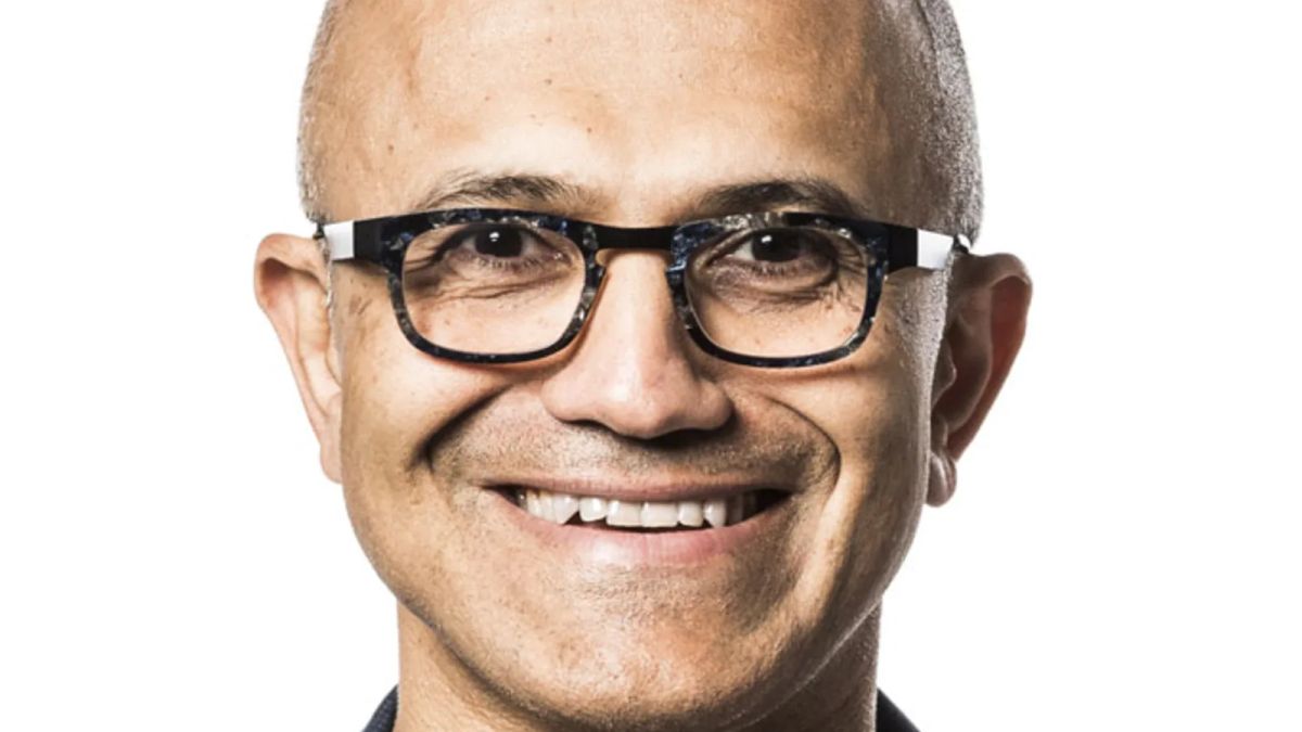 Close-up portrait of Satya Nadella smiling and wearing glasses against a white background